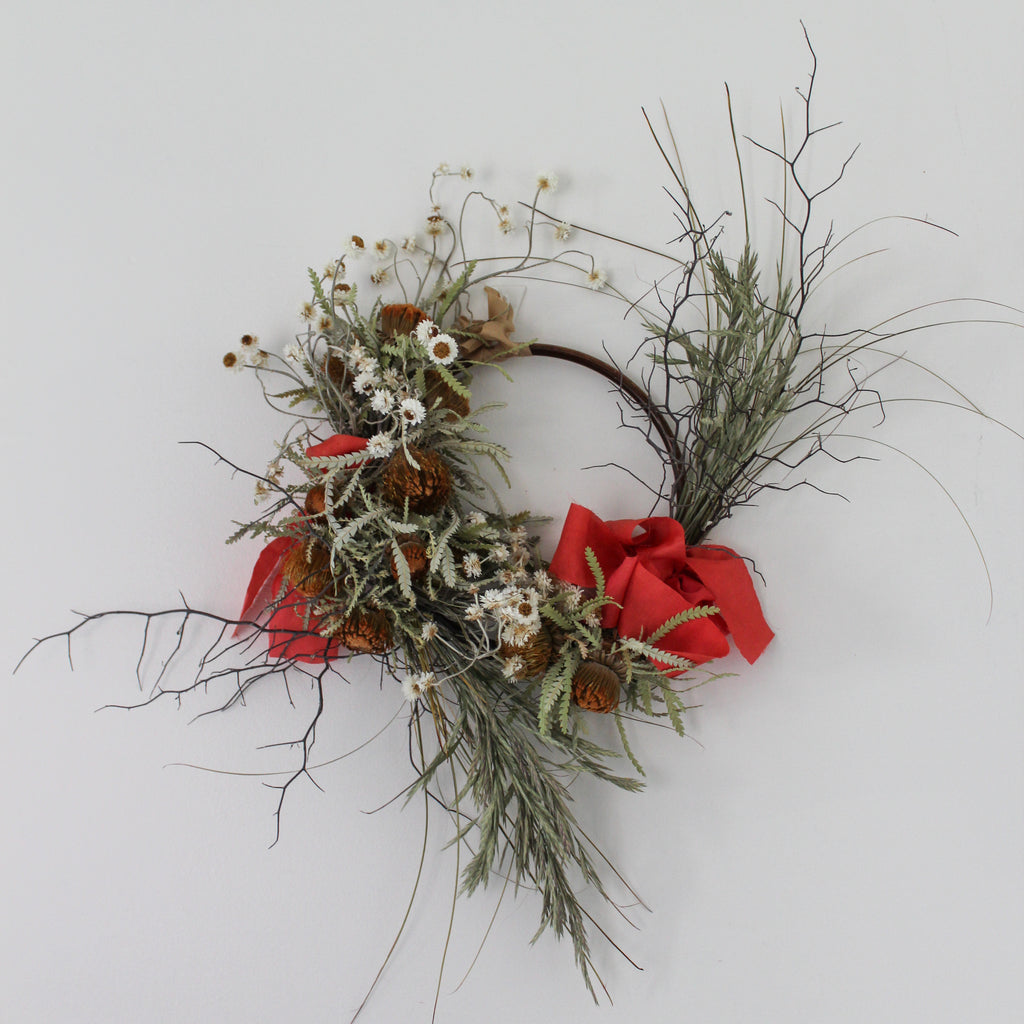 Decorative wreath with red ribbons and natural elements on a white background