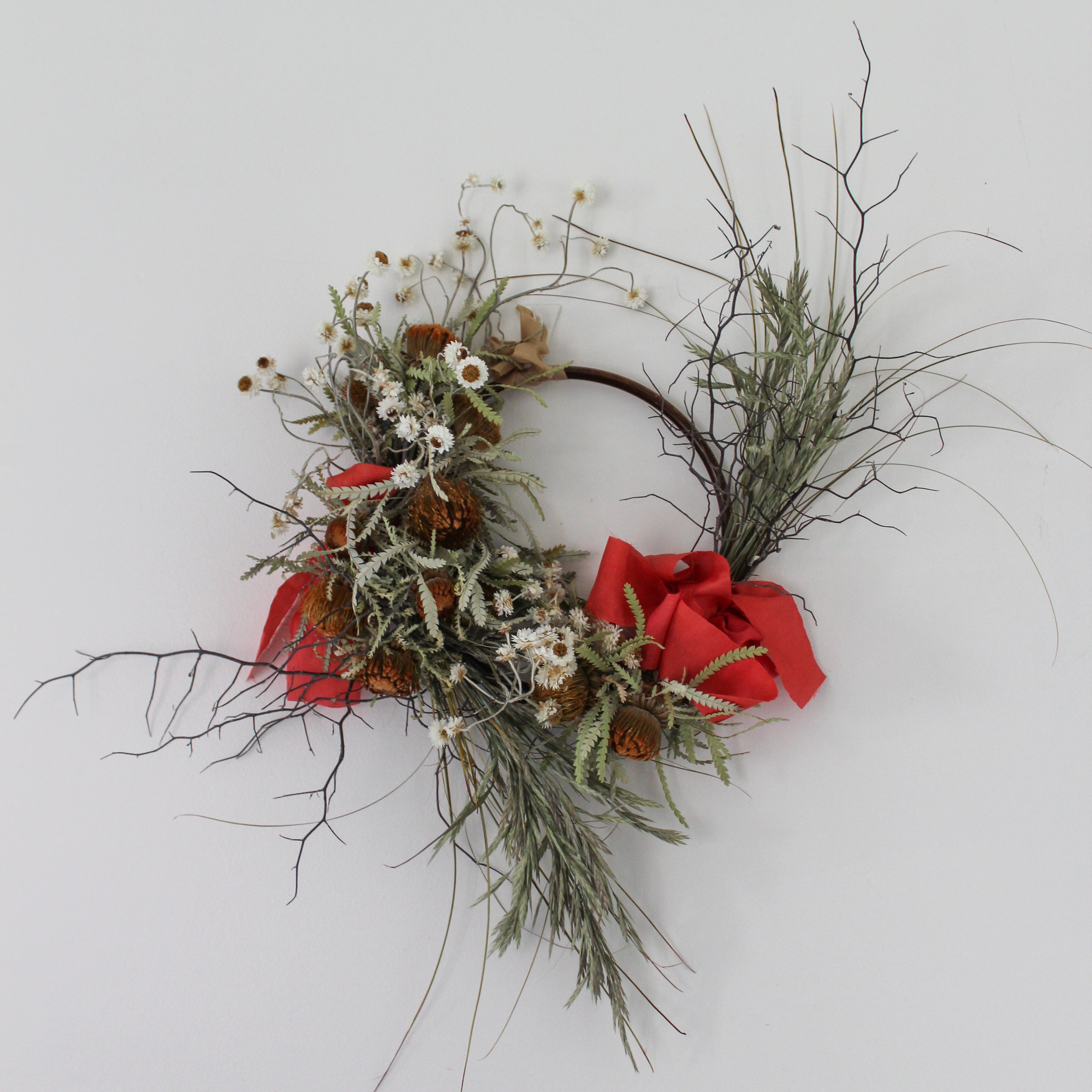 Decorative wreath with red ribbons and natural elements on a white background